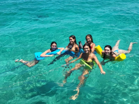 A lively group of friends enjoys a refreshing swim in crystal-clear waters, perfect for a day of fun and relaxation on the water.