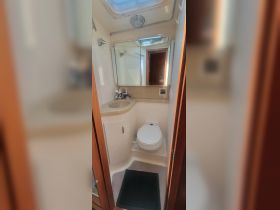 Interior view of a boat bathroom featuring a modern design with a toilet, sink, and mirror — ideal for comfort while at sea.