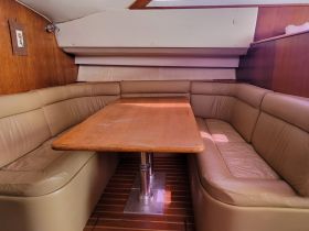 Cozy interior view of a boat's dining area featuring comfortable seating and a wooden table, perfect for relaxing meals on the water.