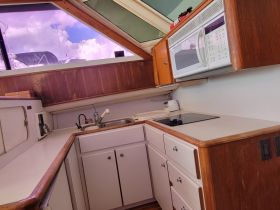 Interior view of a boat's kitchen area, featuring a sink, stove, and microwave — a cozy space for meal preparation while on the water.