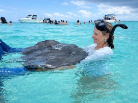 A woman interacts closely with a stingray in the clear turquoise waters, showcasing a unique wildlife experience that highlights the beauty of marine life.