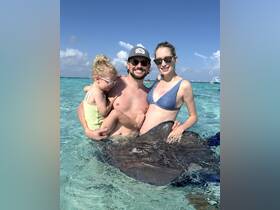 A family enjoys a memorable encounter swimming with a stingray in crystal-clear waters, creating unforgettable moments in a tropical paradise.
