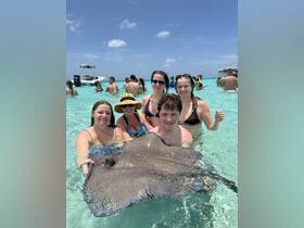 A group of friends interacts with a stingray in shallow waters, showcasing a unique wildlife experience in a tropical setting.