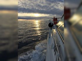 A serene view of a boat cutting through calm waters at sunset, showcasing the beautiful reflections on the surface — perfect for tranquil evening cruises.