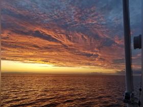 A stunning sunset over the ocean, viewed from a boat, showcasing vibrant colors reflecting on the water — perfect for serene evening cruises.