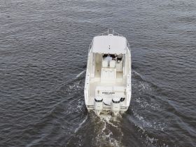 Aerial view of a speedboat named 'Wide Load' cruising through calm waters, showcasing its sleek design and powerful engines.
