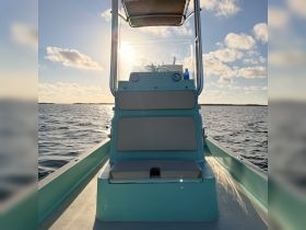 A serene view of the helm and seating area inside a fishing boat, perfect for a day out on the water. The bright sunlight enhances the inviting atmosphere.