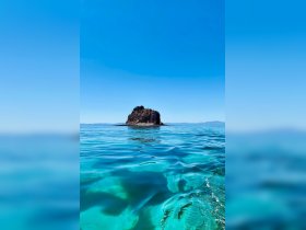 A stunning view of a rocky island surrounded by crystal-clear turquoise waters, perfect for showcasing the beauty of coastal destinations.