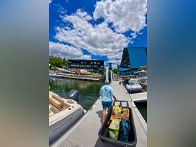 A person walks down the dock, pulling a cart filled with supplies, preparing for a day on the water. The vibrant marina setting adds to the excitement of boating adventures.