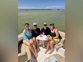 A group of friends enjoys drinks and sunshine on a pontoon boat, capturing the essence of a fun day on the water.