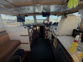 Interior view of a boat's helm and cabin area, showcasing the seating and control console, ideal for fishing trips or leisure cruising.