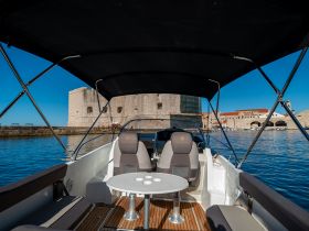 A stylish interior view of a boat's helm and seating area, showcasing a perfect spot for relaxation while enjoying scenic waterfront views.