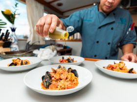 A chef prepares a delicious seafood pasta dish on board, showcasing the culinary amenities available for guests on the boat.