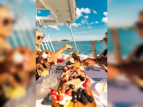 Guests enjoy a beautifully arranged charcuterie board and cocktails aboard a boat, perfect for a luxurious dining experience on the water.