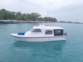 A sleek boat named 'Nihali Pulse' is docked in clear turquoise waters, showcasing its modern design against a backdrop of lush greenery.