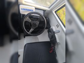 Interior view of a boat's helm and seating area, showcasing the steering wheel and control console, ideal for navigation and comfort while on the water.