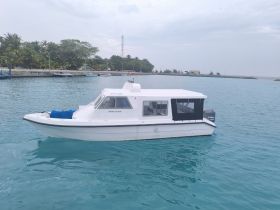 A sleek boat named 'Rihali Puge' docked in tranquil turquoise waters, surrounded by lush greenery — perfect for exploring coastal destinations.