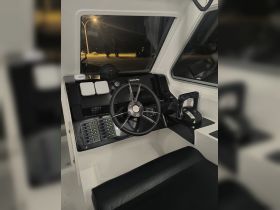 A sleek view of the helm and console area inside a modern boat, showcasing the controls and seating designed for an optimal boating experience.
