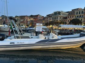 A sleek speedboat docked in a picturesque harbor, showcasing the vibrant waterfront buildings illuminated at dusk.