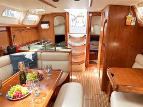 A beautifully arranged interior of a boat cabin featuring a dining area with fresh fruits and champagne, perfect for intimate gatherings or relaxing moments on the water.