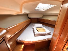 Cozy cabin interior of a boat featuring a neatly made bed with fresh linens and towels, perfect for relaxing during a sailing trip.