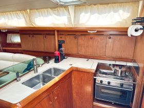 Interior view of a boat's kitchen area featuring a sink, stove, and coffee maker, perfect for preparing meals while on the water.