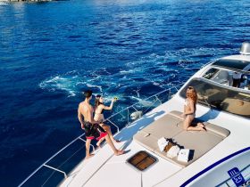 A lively scene aboard a yacht with friends enjoying drinks and sunbathing, perfect for a fun day on the water.