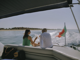 A couple enjoys cocktails on the deck of a yacht, basking in the sun and savoring the beautiful coastal views — an ideal moment for romantic getaways.