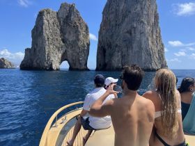 A group of friends enjoys a scenic boat ride near iconic rock formations, capturing the stunning views of the coastline — a perfect moment for adventure seekers.