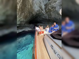A lively group enjoys a boat trip exploring a stunning cave, capturing memories against the backdrop of crystal-clear waters.