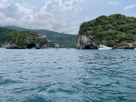 A stunning view of coastal rock formations and boats in the water, showcasing the natural beauty of the area — perfect for sightseeing and exploration.