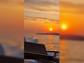 A stunning sunset view from a boat, showcasing the tranquil waters and distant island silhouette — perfect for capturing the serene beauty of evening cruises.