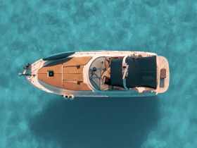 A stunning aerial view of a boat cruising over crystal-clear turquoise waters, showcasing its sleek design and inviting deck space.