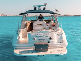 A stunning view of a yacht named 'Adventure' with a captain at the helm, surrounded by vibrant turquoise waters — perfect for luxury boating experiences.