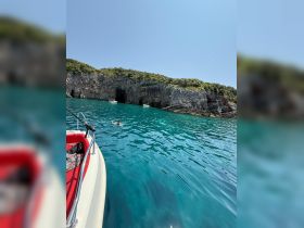 A swimmer enjoys the crystal-clear turquoise waters near a stunning cave, showcasing the beauty of the coastline — an ideal spot for exploration and adventure.