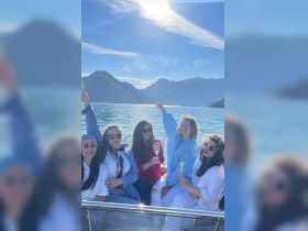 A lively group of friends enjoys a boat party, raising their glasses against a stunning mountain backdrop — perfect for celebrations and memorable outings on the water.