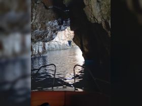 A stunning view from a boat entering a cave, showcasing the natural rock formations and tranquil waters — perfect for adventure seekers exploring hidden gems.