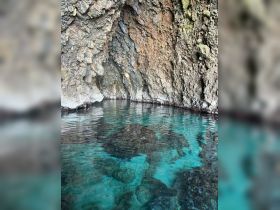 A scenic view of rocky cliffs reflected in clear turquoise waters, creating a tranquil atmosphere perfect for exploring coastal landscapes.