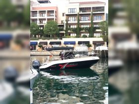 A sleek Marinello speedboat is docked in a picturesque marina, showcasing its stylish design against a backdrop of luxury apartments.
