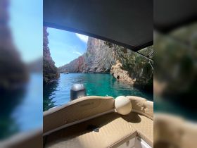 A serene view from the interior of a Marinello boat, showcasing comfortable seating and stunning natural rock formations outside, perfect for exploring hidden coves.