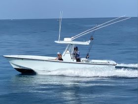 A fishing speedboat navigates the open waters with two individuals onboard, showcasing the thrill of on-water activities.