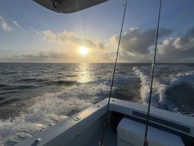 A serene sunset view from a fishing boat, showcasing the tranquil ocean waters and the fading light — perfect for evening fishing trips.