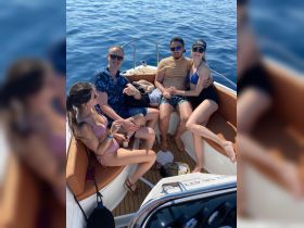 A lively group of friends enjoys a sunny day on a boat, capturing the essence of summer fun and celebration on the water.