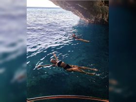 Two individuals enjoy a refreshing swim in the crystal-clear waters of a cave, showcasing the beauty of underwater adventures and exploration.