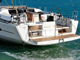A detailed view of the back of a sleek yacht, showcasing its modern design and features as it navigates through clear waters.