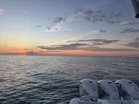 A serene sunset view over calm waters, showcasing the powerful engines of a boat — perfect for evening cruises and tranquil moments on the water.