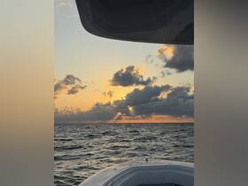 A serene sunset view from the bow of a boat, showcasing the tranquil ocean and dramatic cloud formations — perfect for peaceful evening cruises.