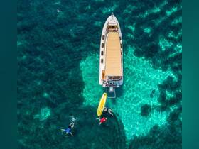 Aerial view of a group enjoying the clear turquoise waters while swimming and paddleboarding near a boat, capturing the essence of a perfect day on the water.