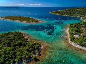 A stunning aerial view of a picturesque coastline featuring lush greenery and crystal-clear waters, perfect for boating adventures and island exploration.