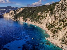 A stunning aerial view of a secluded beach surrounded by cliffs and crystal-clear waters, perfect for exploring the natural beauty of the coastline.